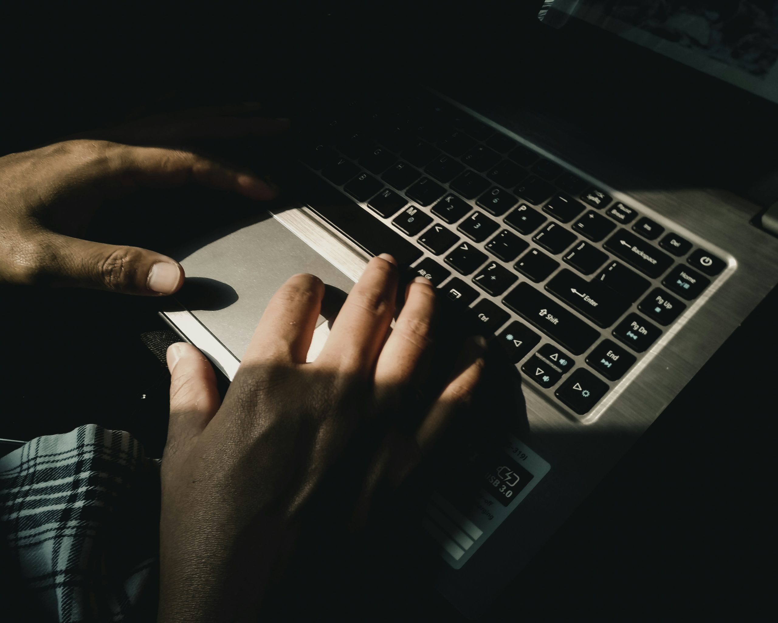 person typing on a laptop in a dark room